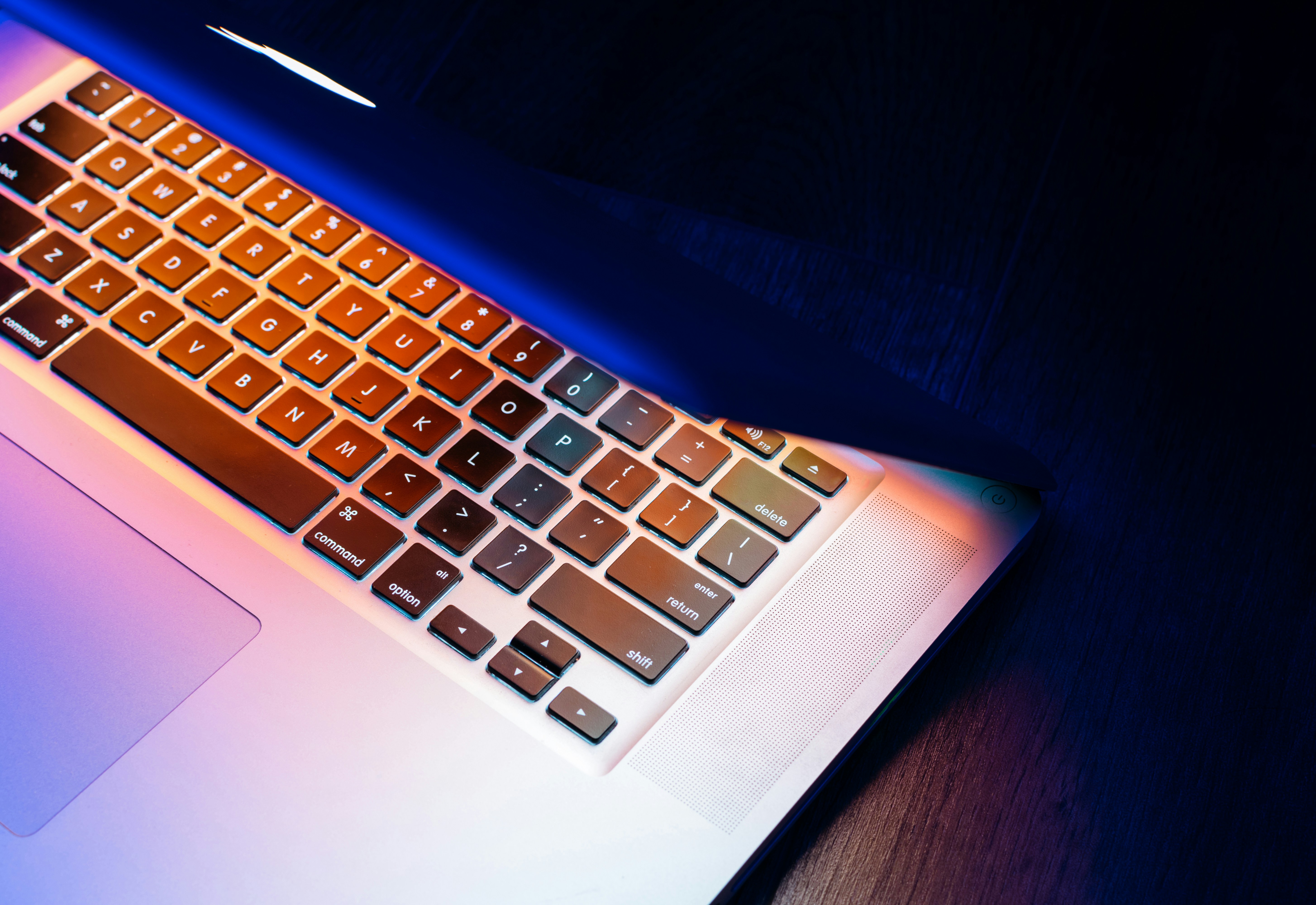 Neon screen reflecting on a macbook keyboard